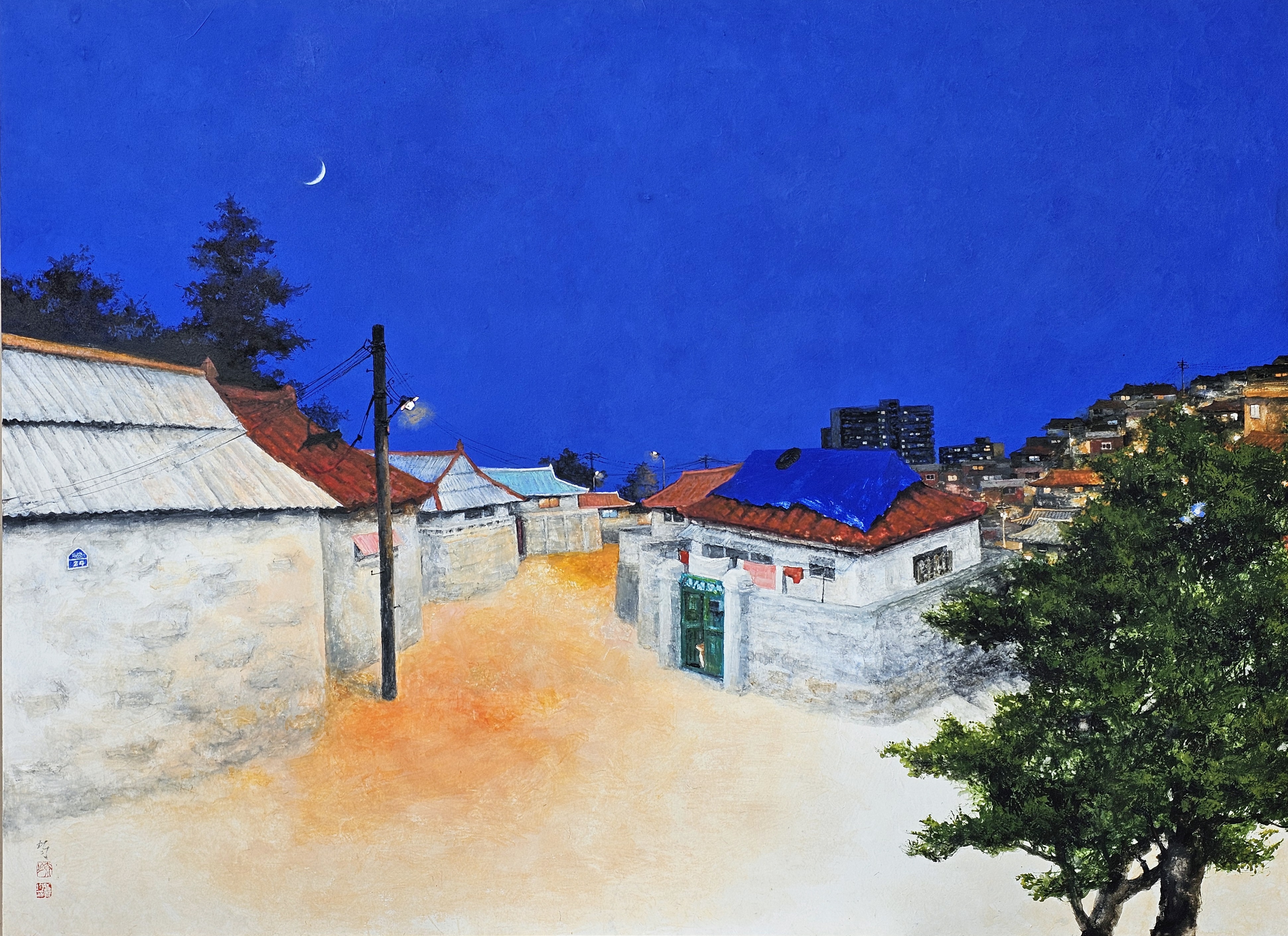 0899b44d993f78b104e3fcf71a9dfa1f.jpg 강내균 <평창풍경> 작품 이미지. 짙은 남청색 하늘에 초승달이 뜬 밤, 노란 가로등 아래 골목과 붉은 지붕의 낮은 돌담집이 이어진 풍경이 펼쳐진다. 초록 대문이 보이고 화면의 오른쪽엔 나무, 멀리 언덕에는 불 켜진 주택과 아파드가 펼쳐진다.